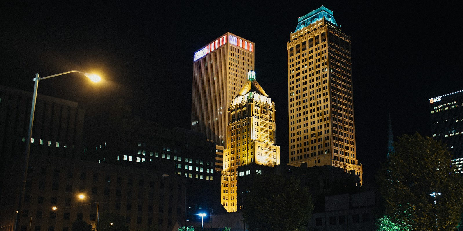 Nighttime in Downtown Tulsa reveals a stunning architectural legacy, where historic Art Deco landmarks stand alongside modern skyscrapers. This view highlights the city's identity as a hub for both oil-era opulence and contemporary urban living.